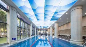 厦门Fliport Garden Hotel Xiamen Airport的一座建筑内的游泳池，天花板呈蓝白相间。