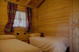 una camera con due letti e un orsacchiotto che si siede tra loro di Chalet Eco-Lodge Faè a Madonna di Campiglio Altre 24 foto