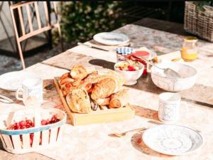un tavolo con vassoio di pane e ciotole di cibo di B&B Château Légier a Fontvieille