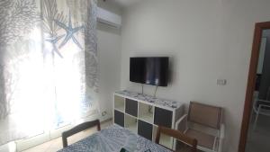 Zimmer mit einem Tisch und einem TV an der Wand in der Unterkunft La Casa del Ferroviere in Letojanni