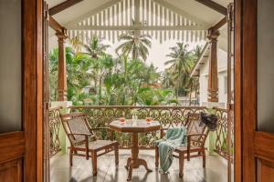 een balkon met een tafel en stoelen en palmbomen bij Sanctuary by RÊVE Escapes - Premium 3 BHK Villa with Private Pool Near Morjim Beach in Siolim