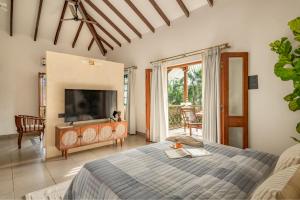 een slaapkamer met een bed en een televisie in een kamer bij Sanctuary by RÊVE Escapes - Premium 3 BHK Villa with Private Pool Near Morjim Beach in Siolim