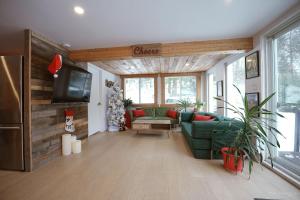 - un salon avec un canapé vert et une télévision dans l'établissement Spa et Waterfront - Cachette du Petit Lac, à Chertsey