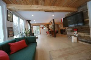 un salon avec un canapé vert et une télévision à écran plat dans l'établissement Spa et Waterfront - Cachette du Petit Lac, à Chertsey