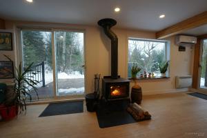 un salon avec un poêle à bois devant une fenêtre dans l'établissement Spa et Waterfront - Cachette du Petit Lac, à Chertsey