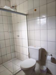 a white bathroom with a toilet and a shower at Aquarela Suítes in Piúma