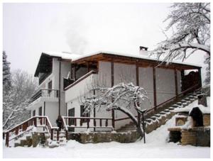 una casa cubierta de nieve con un árbol delante en Guest rooms Voneshcha Voda, en Voneshta Voda