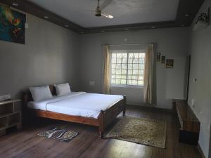 a bedroom with a bed and a window at Coorg Ashiyana in Kushālnagar