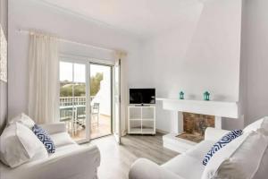 Elle comprend un salon doté d'un mobilier blanc et d'une cheminée. dans l'établissement Villa Can Ernest, à Cala Galdana