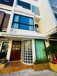 een wit huis met een bruine deur en ramen bij Florent House in Chiang Mai