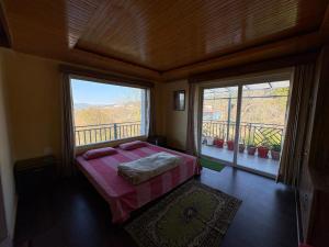 a bedroom with a bed and a balcony with two windows at Tapas in Champawat
