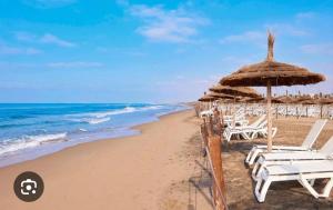 a beach with chairs and an umbrella and the ocean at Seule résidence accès directe plage in Saïdia