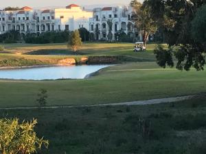 a golf course with a pond in front of a large white house at Seule résidence accès directe plage in Saïdia