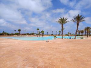 a swimming pool with palm trees and a bench at Seule résidence accès directe plage in Saïdia