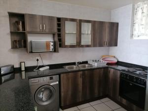 a kitchen with a washer and a sink and a dishwasher at Inyoni Rocks Cabanas 42 in Amanzimtoti