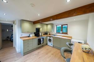 a kitchen with green cabinets and a table with chairs at Stather Cottage in Burton upon Stather
