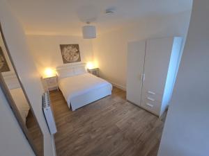 een kleine slaapkamer met een wit bed en een kast bij 2 Bed Apartment with Harbour Views Apt 2 in Cobh +1 foto