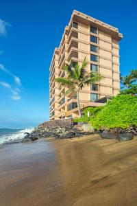 拉海纳Maui Kai Condos - No Resort Fees的海滩上的一栋建筑，周围有棕榈树和大海