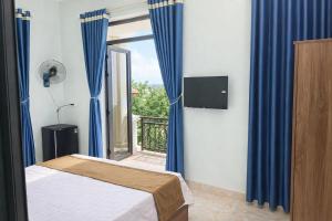 a bedroom with a bed and a window with blue curtains at Chely Hotel in Mù Cang Chải