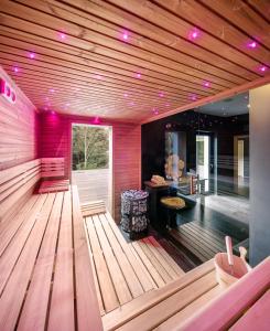 a room with a sauna with wooden floors and pink lights at Pytloun Wellness Hotel Harrachov in Harrachov