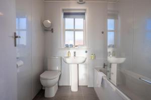 a white bathroom with a toilet and a sink at Shore Cottage - Lower Largo in Lower Largo +42 photos