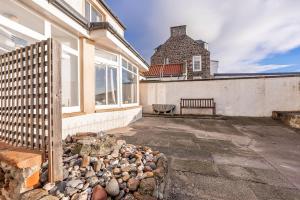 a bench sits outside of a house with a fence at Shore Cottage - Lower Largo in Lower Largo