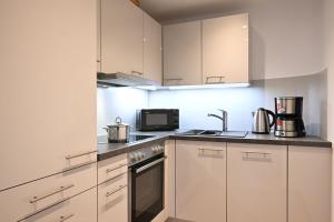 a kitchen with white cabinets and a sink and a microwave at Ferienwohnung Nau in Oberstdorf +5 photos