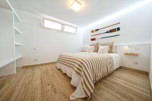 een witte slaapkamer met een bed met een gestreepte deken bij Royal Blue San Agustin in San Bartolomé