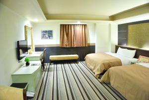 Habitación de hotel con 2 camas y escritorio en Ying Zhen Hotel, en Taoyuan