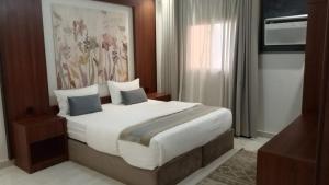 a bedroom with a large bed with white sheets and blue pillows at شقق سكنية بالخالدية in Al ‘Awālī