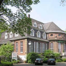 een groot bakstenen huis met twee auto's er voor geparkeerd bij Hotel Casino im Park in Kamp-Lintfort