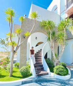 a woman standing in front of a house with palm trees at HiDra Homestay in An Tịnh +29 photos