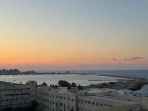 a view of the ocean from a city at sunset at Apartment in Elshatby in Alexandria