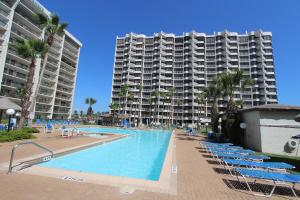 Una piscina con sillas y un gran edificio. en Royale Beach and Tennis Club, en South Padre Island