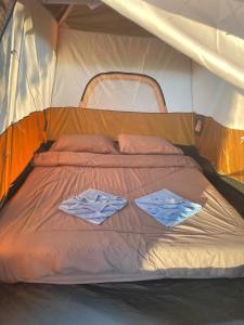 een bed in een tent met twee handdoeken erop bij Kohkood camp in Ban Khlong Mat