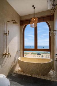 a large tub in a bathroom with a large window at HiDra Homestay in An Tịnh