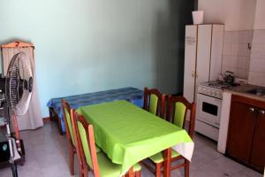 een keuken met een groene tafel en stoelen en een koelkast bij Clau Propiedades in San Antonio Oeste