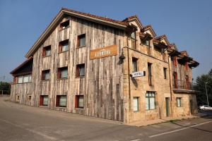 un antiguo edificio de madera al lado de una calle en Hotel La Alfonsina en Santibáñez de Villacarriedo