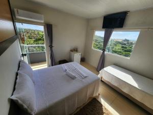 a bedroom with a white bed and two windows at Estalagem Solar das Dunas in Pirambu