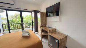 een slaapkamer met een bed met een televisie en een bureau bij Summer of Surf Hostel Ungasan Uluwatu in Jimbaran