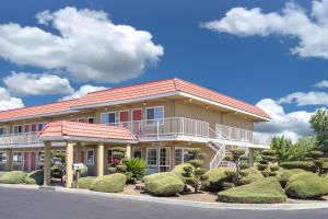 un grand bâtiment avec un balcon et quelques buissons dans l'établissement Days Inn by Wyndham Turlock, à Turlock