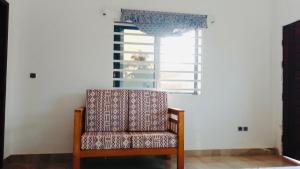a chair sitting in a room with a window at Cozy studio I with AC and fan in Akassato