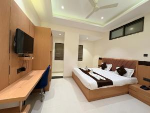 a bedroom with a bed and a desk and a television at Hotel JK Palace Newly Renovate in Shirdi +16 photos
