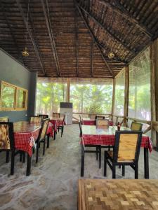 a dining room with tables and chairs and windows at Jangwani Riverview Suits in Mto wa Mbu