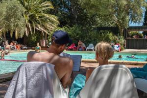 a man and a woman sitting in chairs by a swimming pool at Camping la Peiriere - Chalet & Mobile-home in Tuchan