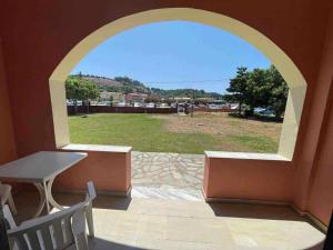 une fenêtre cintrée avec une table et un banc sur une terrasse dans l'établissement Exclusive Alexandra Apartments, à Sidari