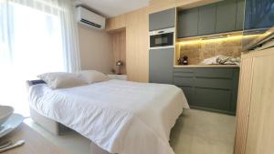 a bedroom with a white bed and a kitchen at Studio du Soleil in Le Val