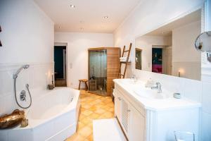 een badkamer met twee wastafels, een bad en een douche bij Strömbergs Merle in Oberstaufen