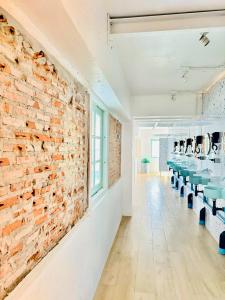 a brick wall in a room with tables and chairs at Easy Monday Capsule Hotel Bangkok in Bangkok