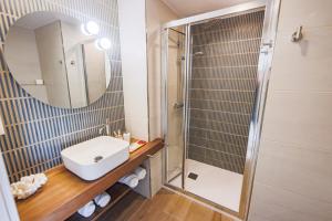 een badkamer met wastafel en douche met spiegel bij Apartamentos PRAIA DO CANSORRO in Camariñas +26 foto's